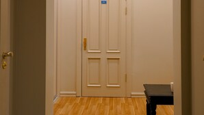 Un couloir avec une porte à deux battants, une petite table et un tapis posé sur un plancher en bois.