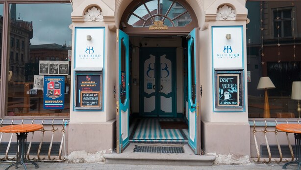 L’entrée de l’hôtel Bluebird, avec son sol à carreaux et ses portes ouvertes.