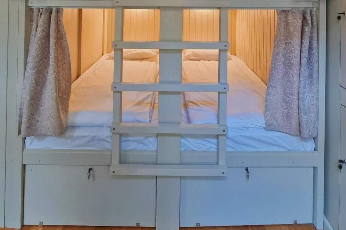 Habitación con literas, paredes de madera y una escalera.