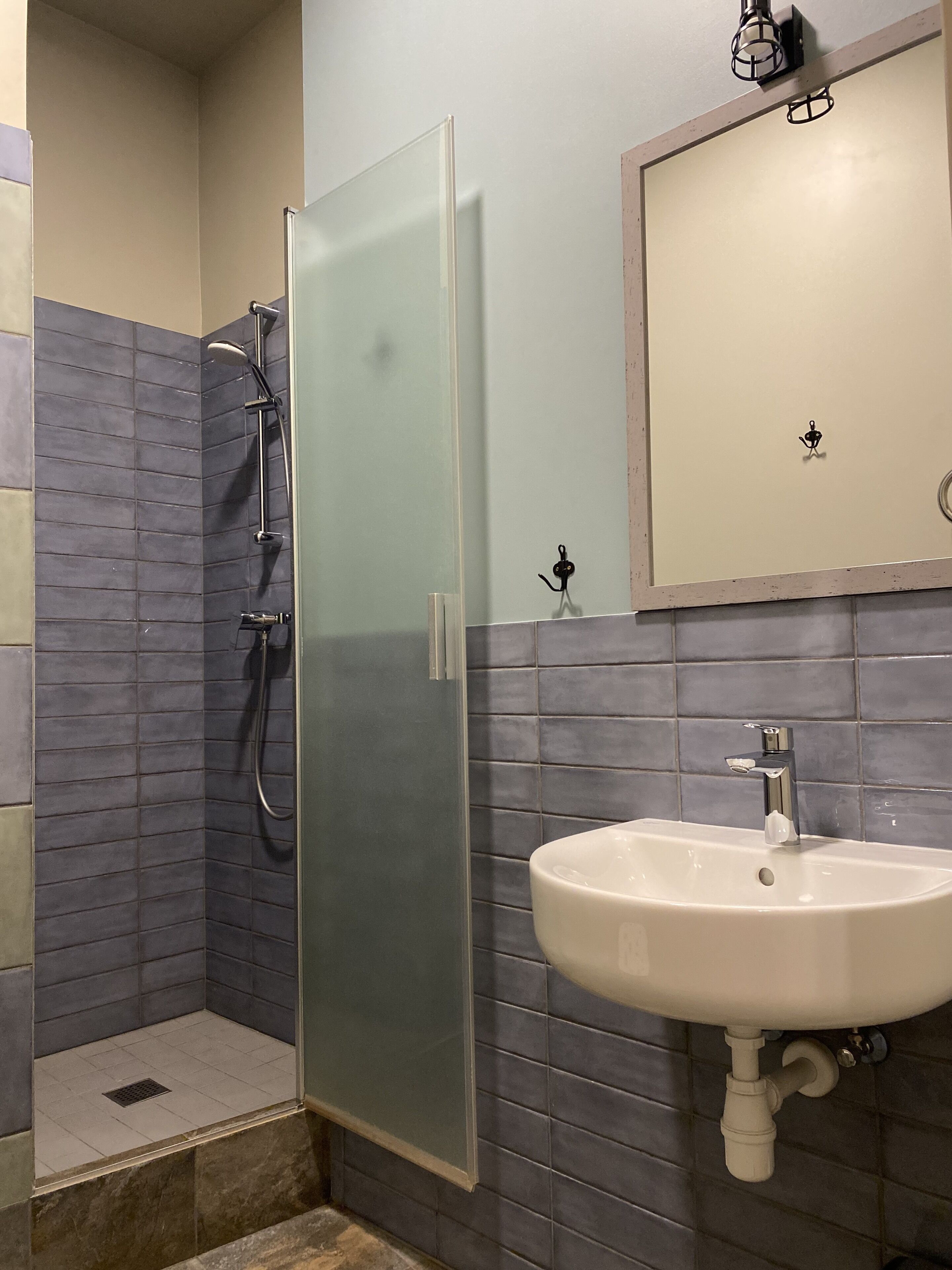 A bathroom with a glass shower enclosure, a sink with a chrome faucet, and a mirror above the sink.