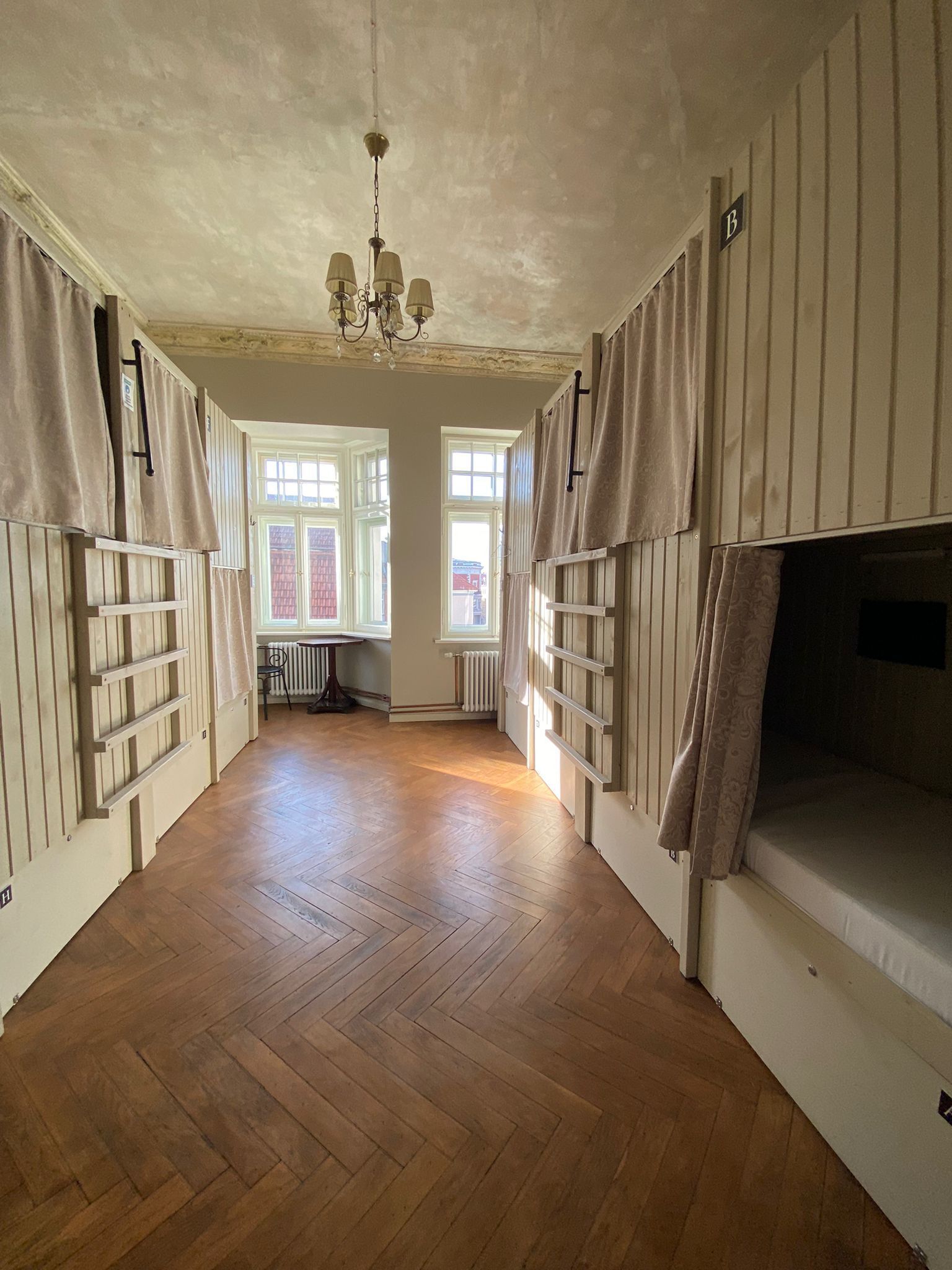 Ein Zimmer mit Holzböden, einem Kronleuchter und großen Fenstern.