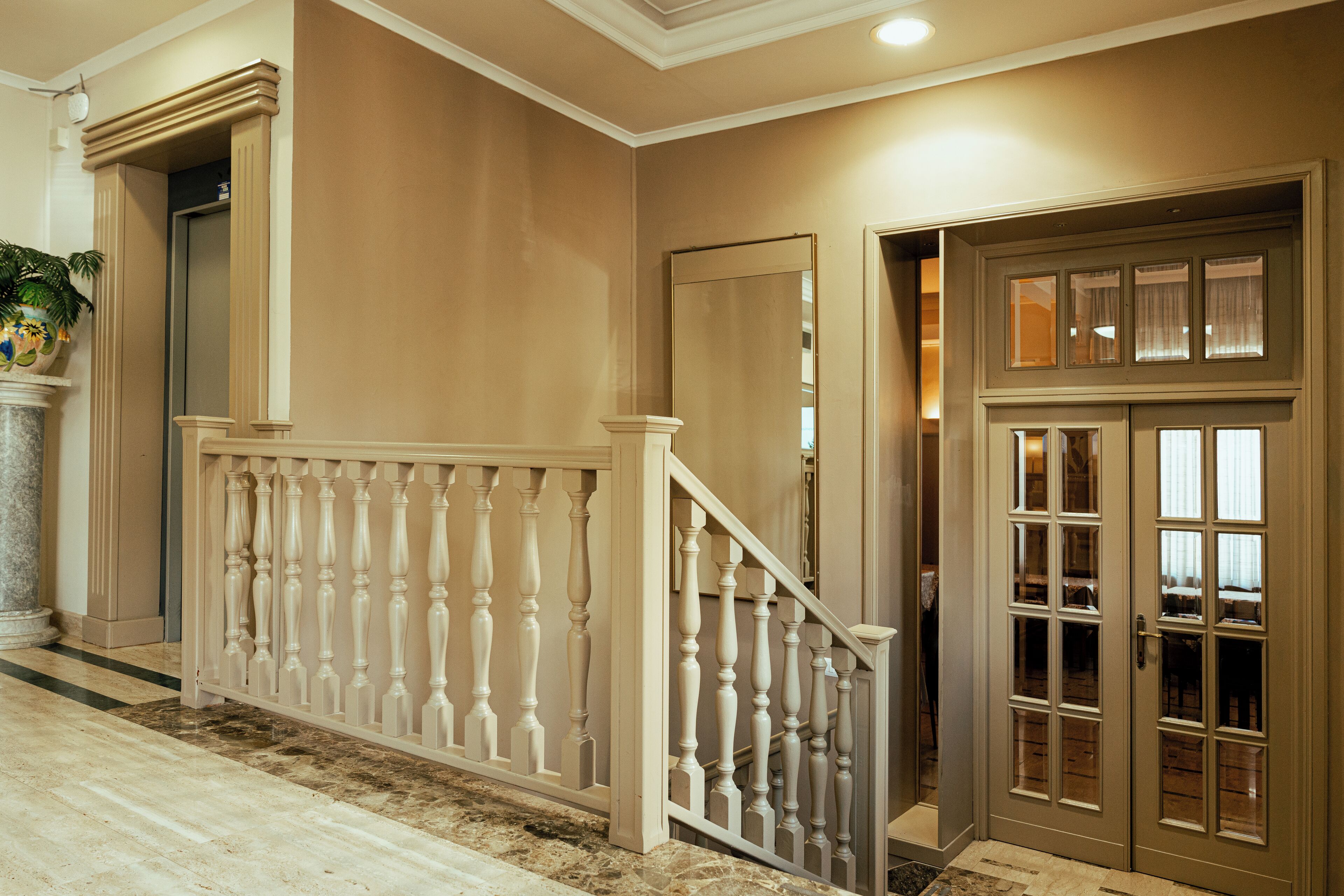 A grand staircase with a balustrade leading to a door with multiple glass panels.