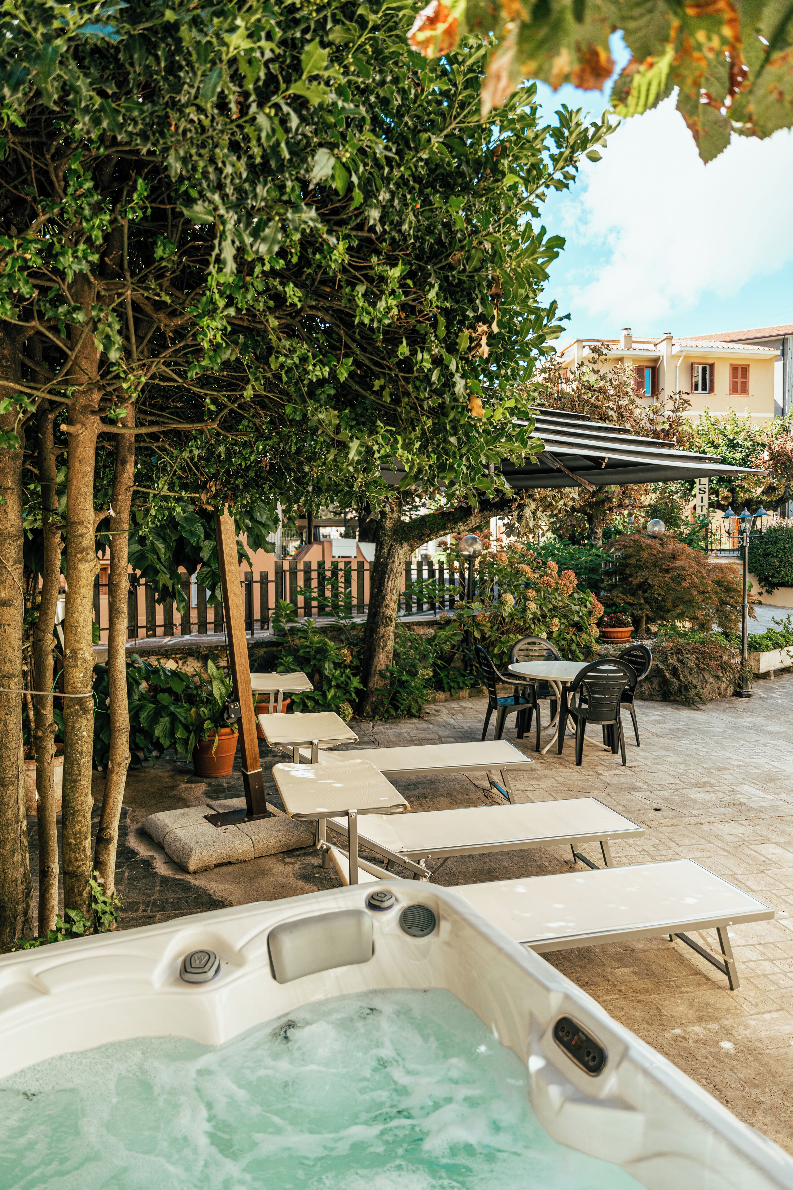 Et spa-område med jacuzzi, liggestole og en pergola, der giver skygge.