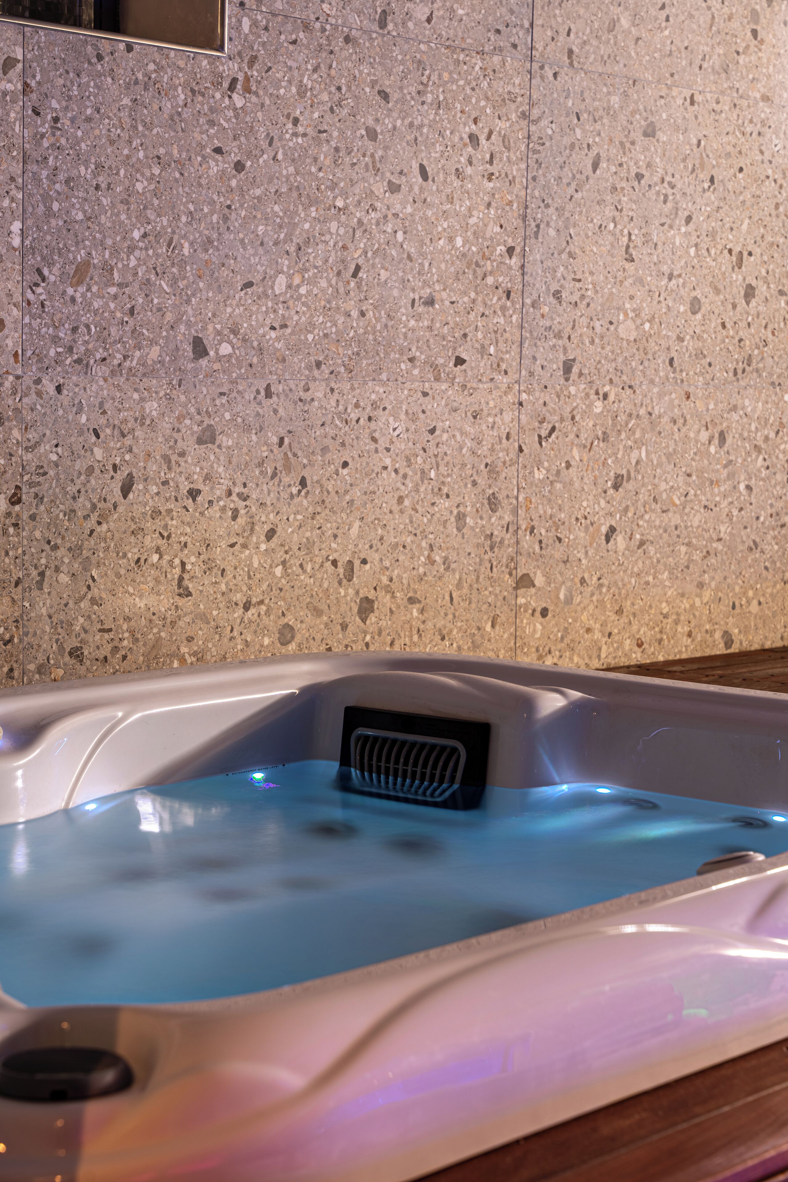 Een whirlpool met ingebouwde verwarming, voor een geaderde stenen muur.