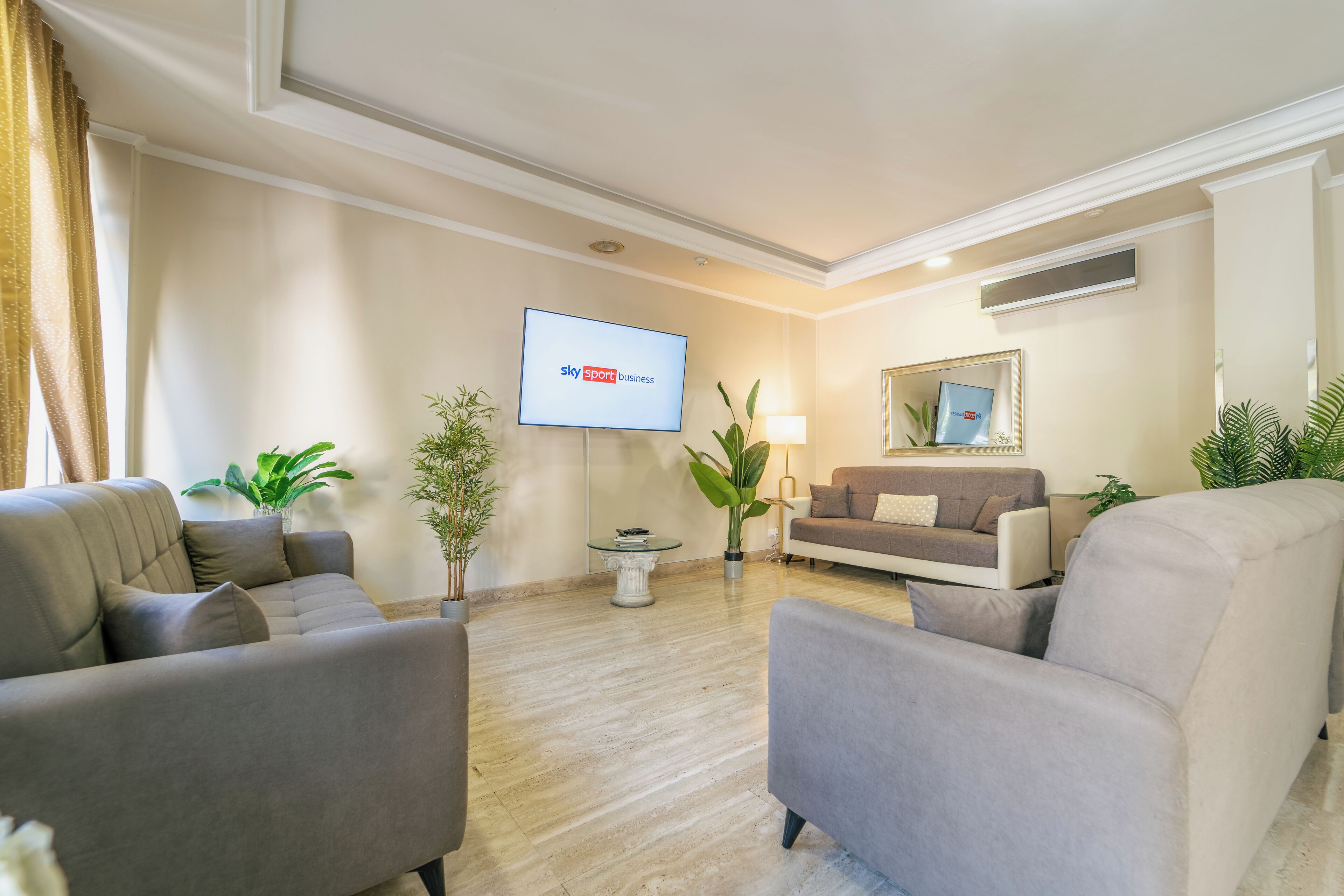 Una sala de estar moderna con un televisor de pantalla plana, dos sofás y plantas en macetas.