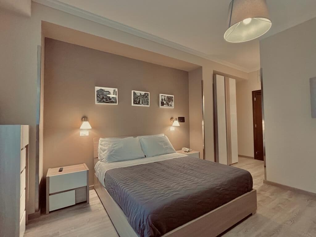 Una camera da letto moderna con un letto, comodini, luci a parete e quadri incorniciati.