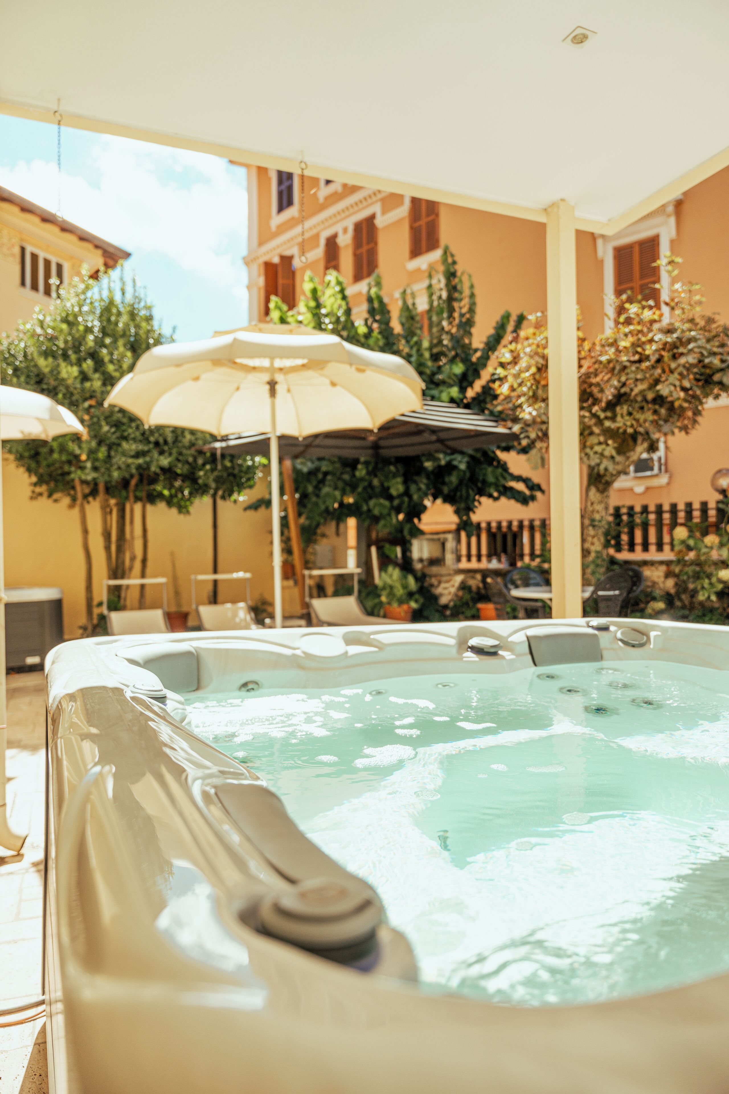 Un jacuzzi en un patio exterior con sombrillas y plantas en macetas.