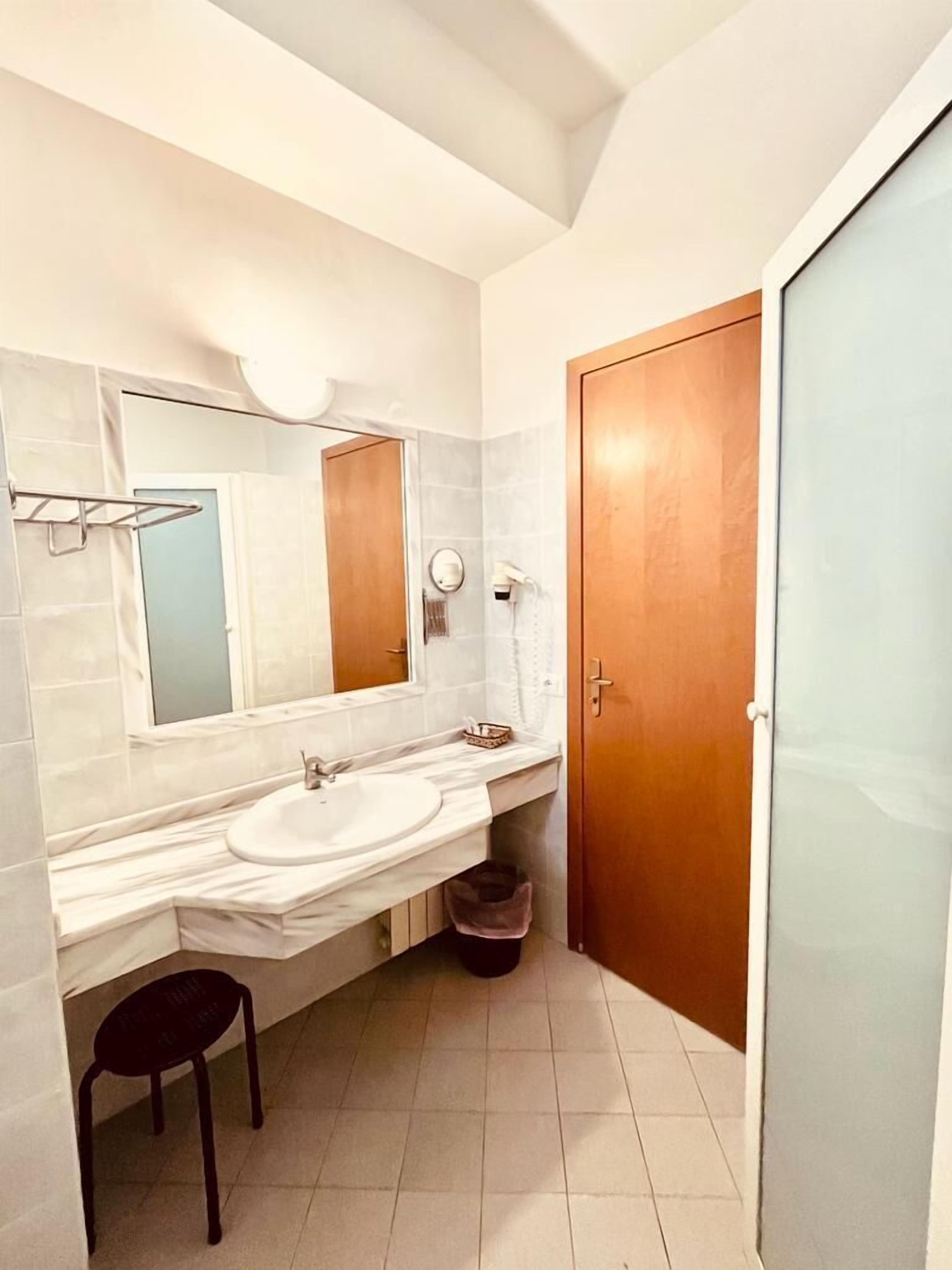 A bathroom with two sinks, a large mirror, a towel rack, and a wooden door.