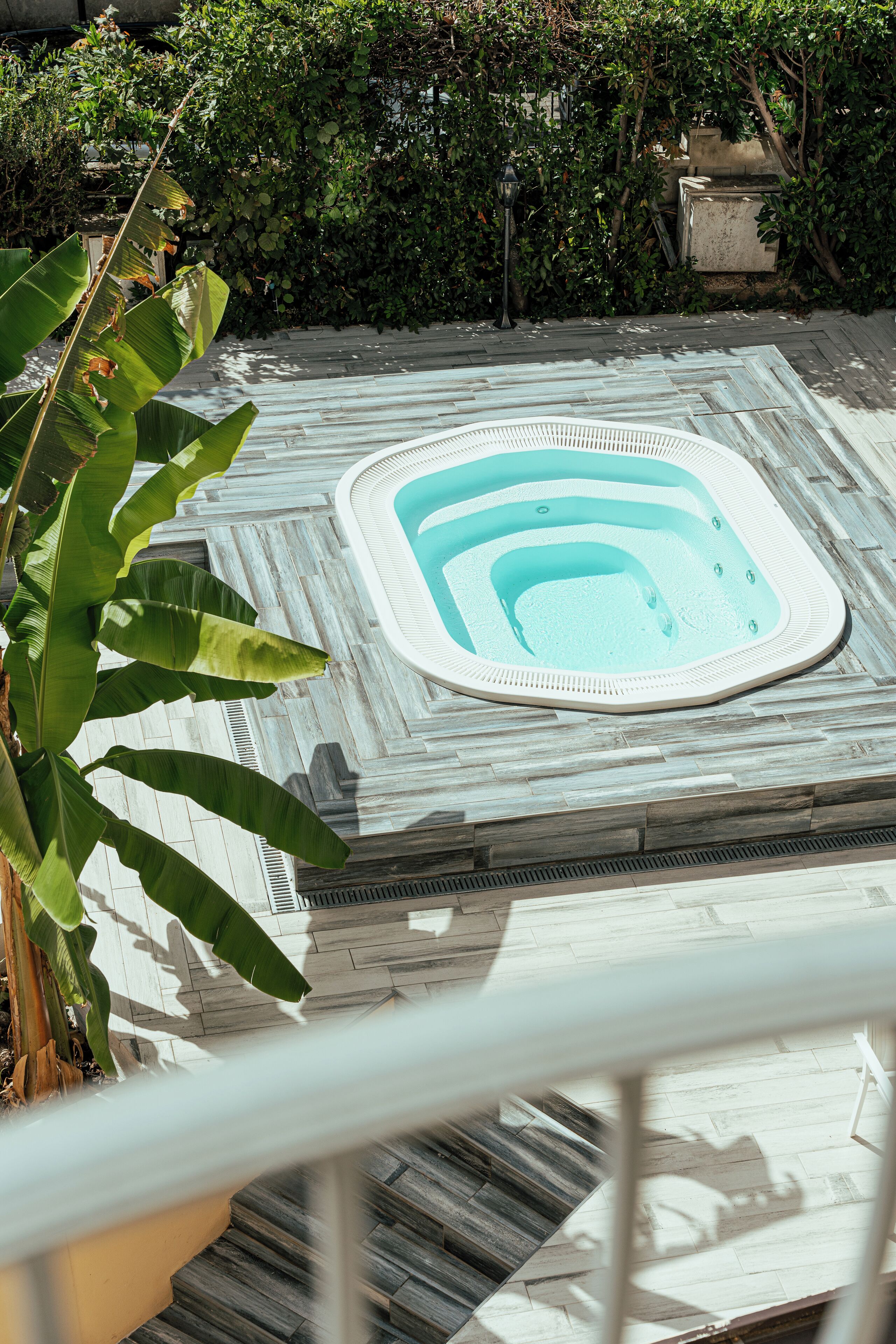 A rooftop pool with a tiled deck and a view of surrounding greenery.