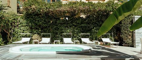 A swimming pool with lounge chairs and a hedge in the background.
