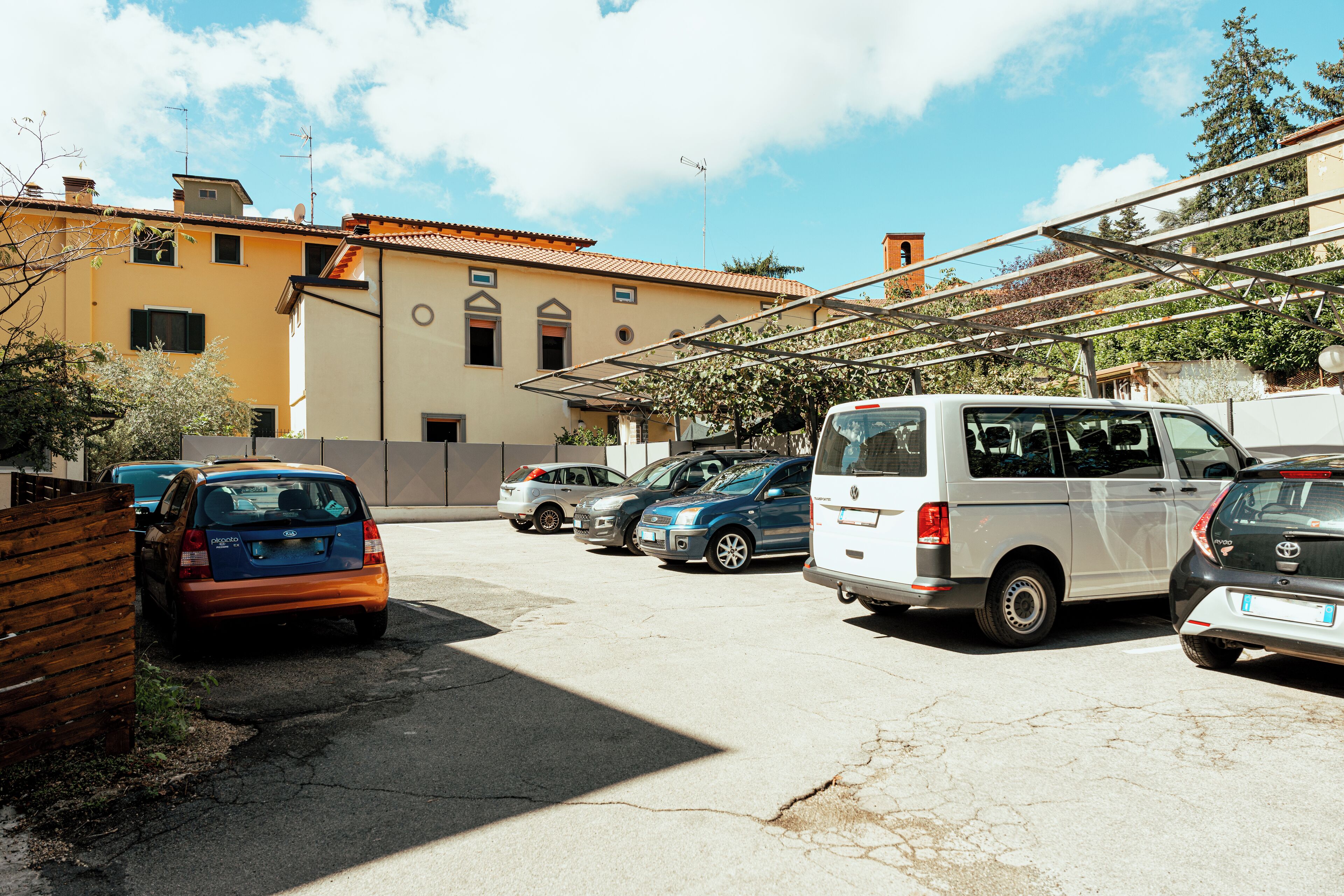 Un estacionamiento con varios coches y un edificio con tejado de azulejos.