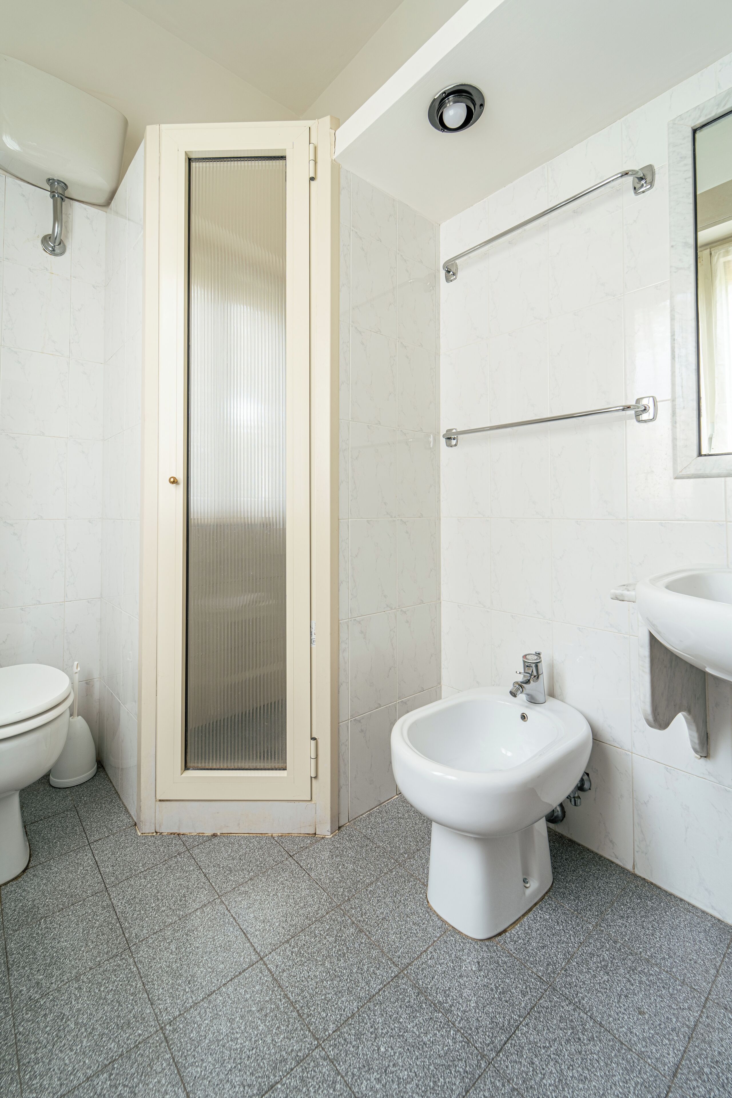 Un baño con inodoro, bidé y cabina de ducha.