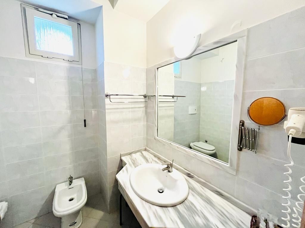 A bathroom with a bidet, a sink, a mirror, and a toilet.