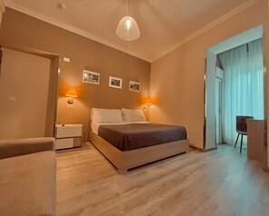 A bedroom with a bed, bedside lamps, a chair, and a door leading to another room.