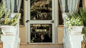 A hotel entrance with a double door, steps leading up to it, and potted plants on either side. - ALBERGO RISTORANTE BELSITO FIUGGI Nhost (Fiuggi)