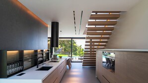 A modern kitchen with a central island, built-in appliances, and a dining area with a view. - Casa Palmera, Casa Palmera (Rhodes)