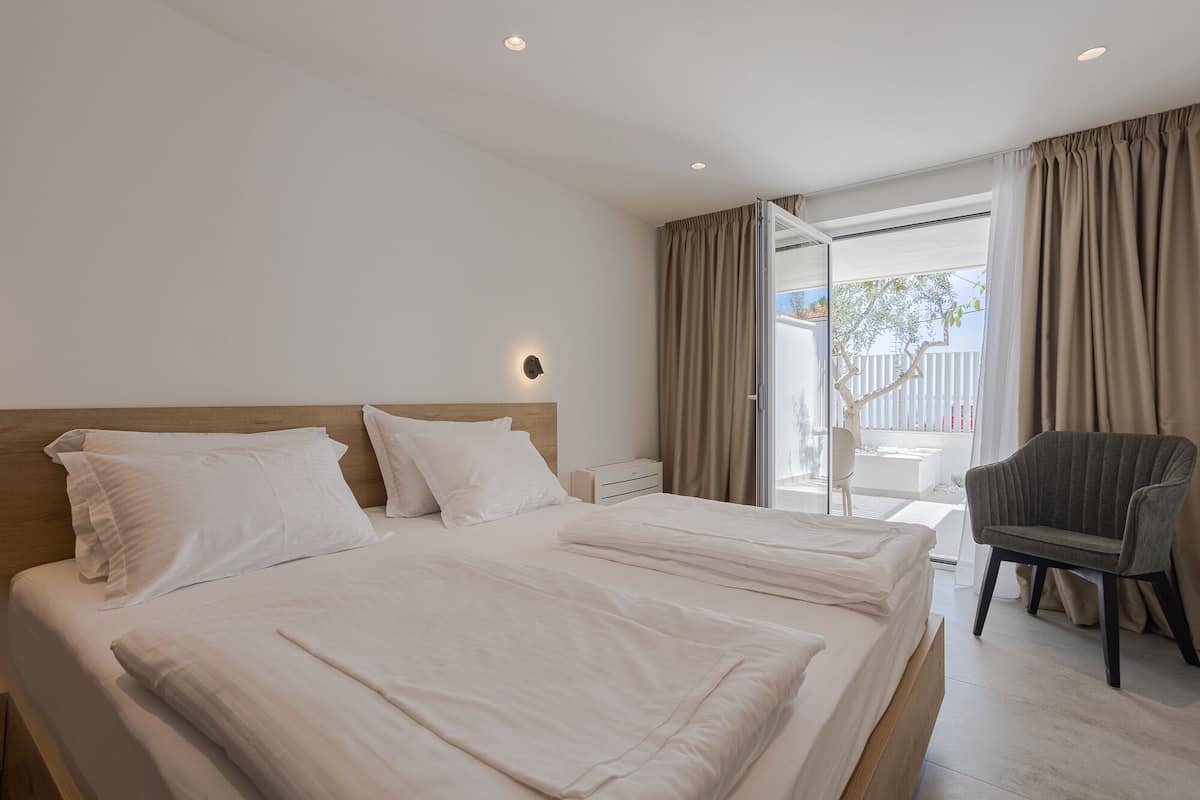 A hotel room with a large bed, a chair, and a view of the outdoors.