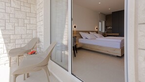 A modern bedroom with a large bed, a nightstand, and a seating area with a table and chairs. - Villa Miki (Podstrana)