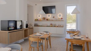 A modern kitchen with a built-in coffee machine, a microwave, and a toaster. There are two dining tables with chairs, and a large window providing natural light. - Villa Miki (Podstrana)