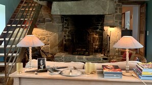Et hyggeligt rum med en stenvæggepejs, en træbænk og en trappe.