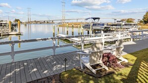Un quai avec des bateaux, une terrasse en bois et des sièges extérieurs.