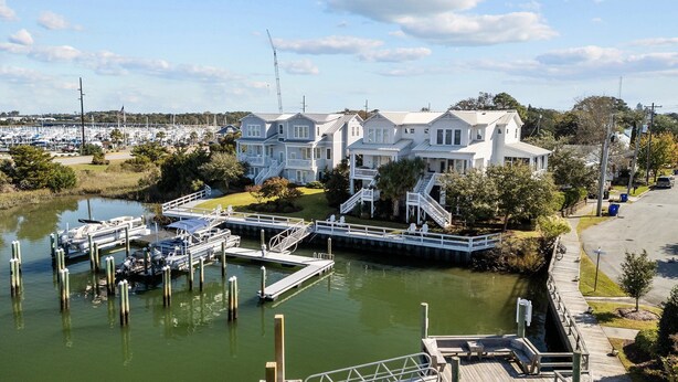 Une propriété située au bord de l’eau, dotée d’un quai, d’une marina et d’une grande maison blanche à plusieurs étages et agrémentée de balcons.