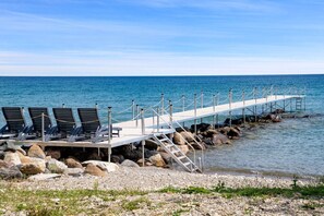 A pier with lounge chairs and a staircase leading to a rocky shoreline. - Skipping Rock Log Cabin: Cozy Charm & Hot Tub Bliss (Meaford)