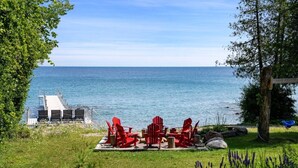 A deck with red Adirondack chairs overlooking a body of water.