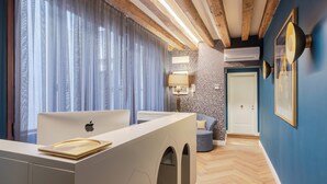 A modern room with a white desk, an Apple laptop, a blue wall, a wooden ceiling, and a patterned rug. - 286 Piazza San Marco (Venice)
