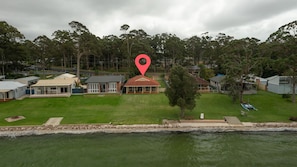A residential area with houses, a grassy lawn, and a body of water. - Island View by Experience Jervis Bay (St Georges Basin)