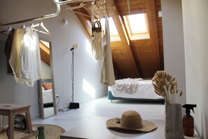 Un dormitorio con techo inclinado, una cama, una lámpara colgante, un espejo y una ventana.