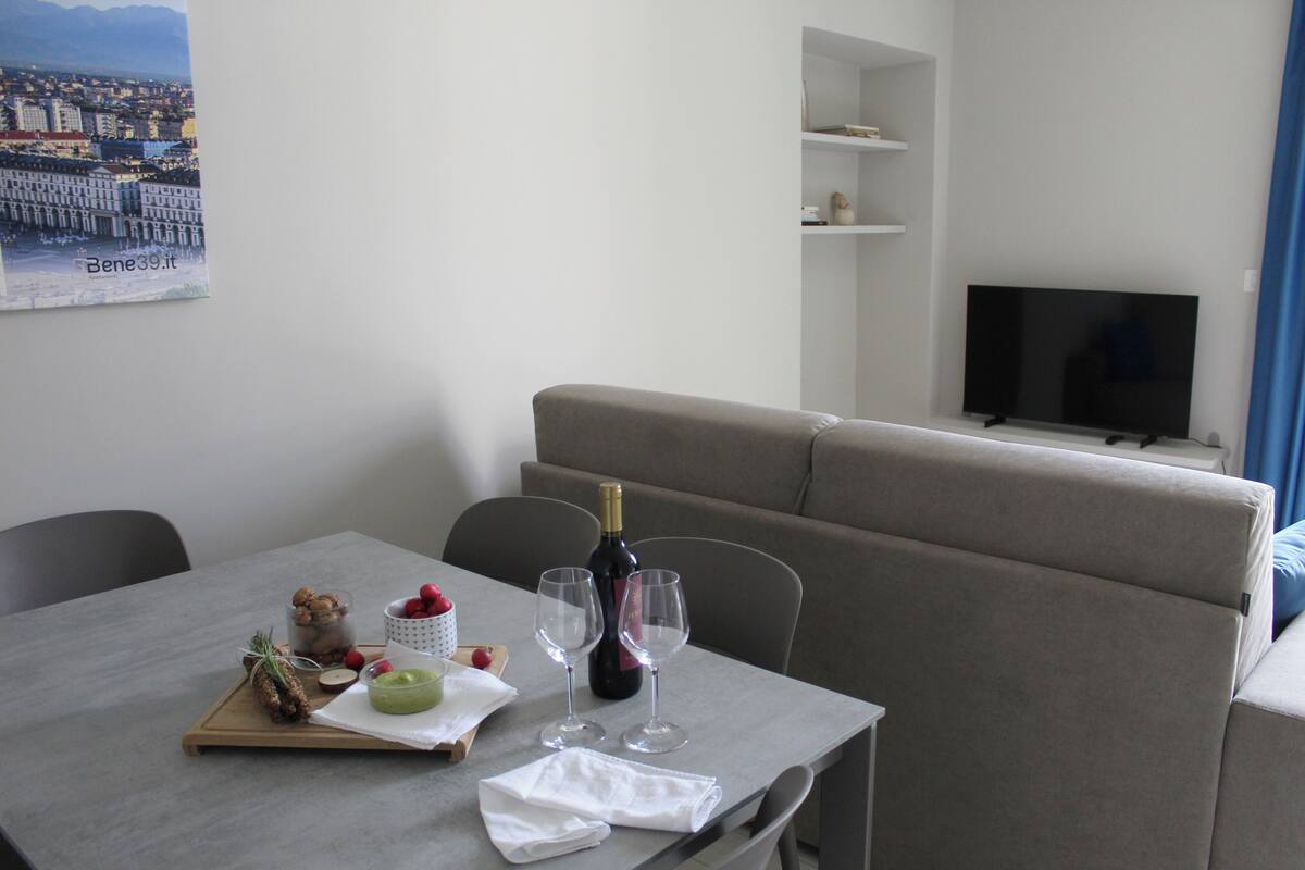 Ett hotellrum med ett matbord dukat för två personer, en flaska vin och ett bricka med mat och dryck.