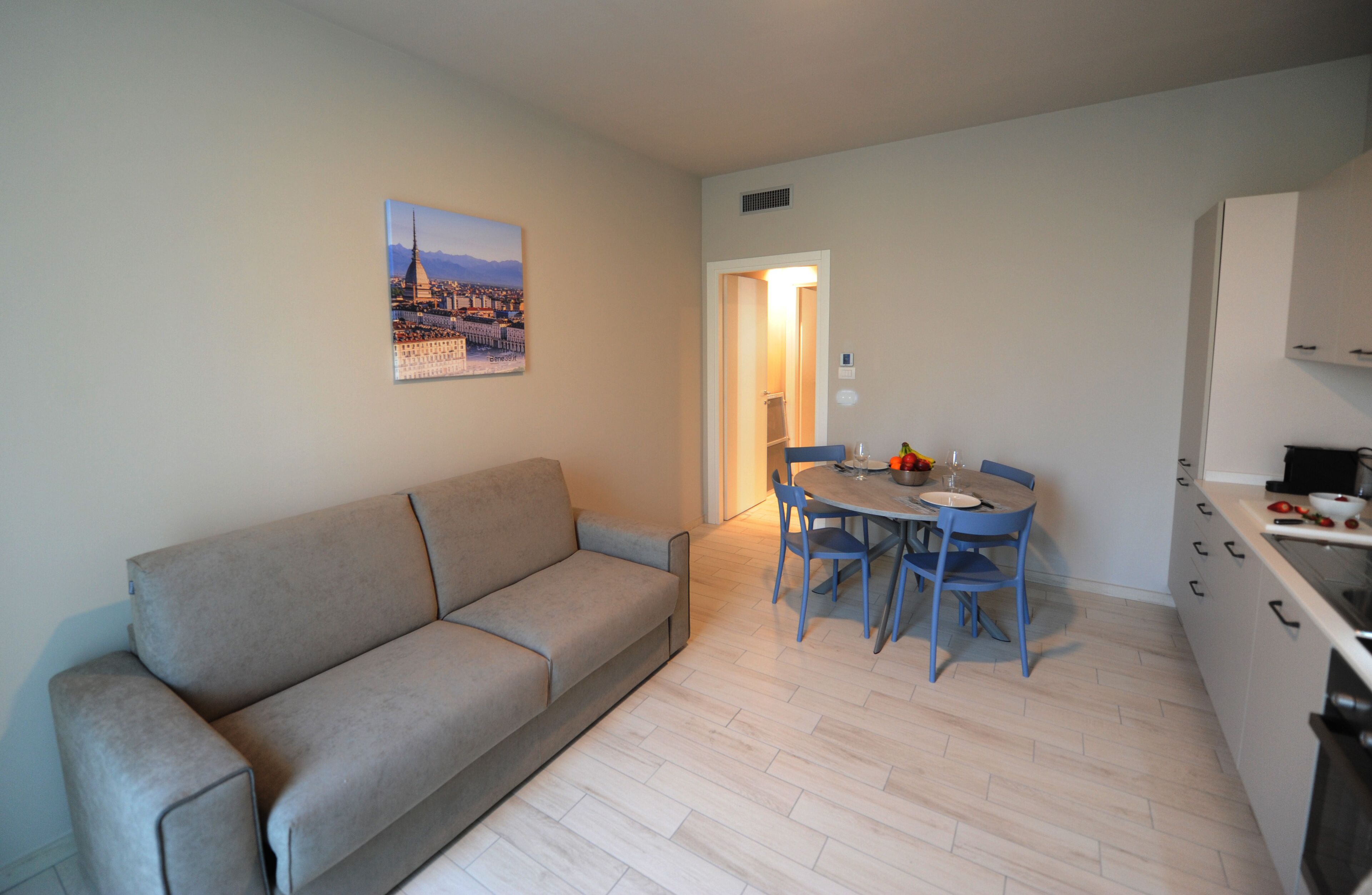 A compact living space with a sofa, a dining table with chairs, and a kitchenette.