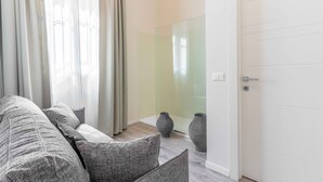 A modern living room with a grey sofa, a glass partition, and two grey vases.