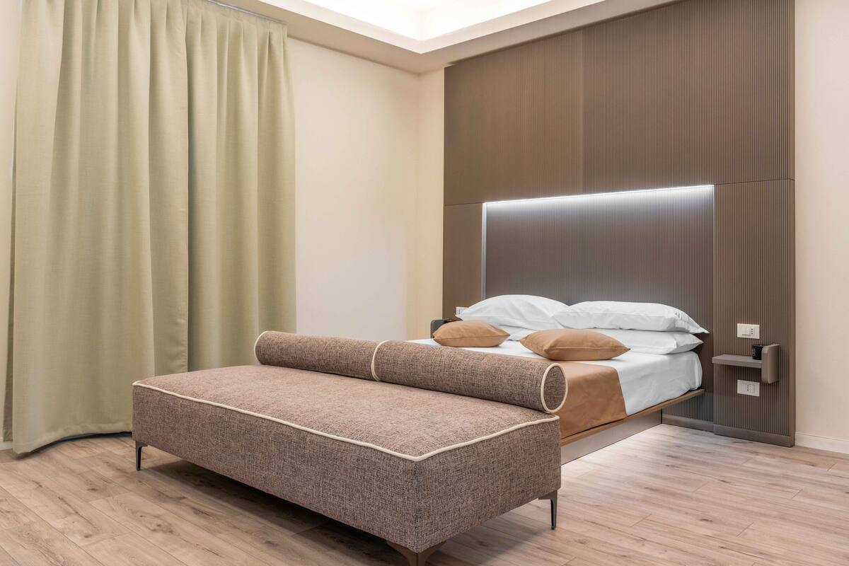 A modern bedroom with a bed, a sofa, and a bedside table.