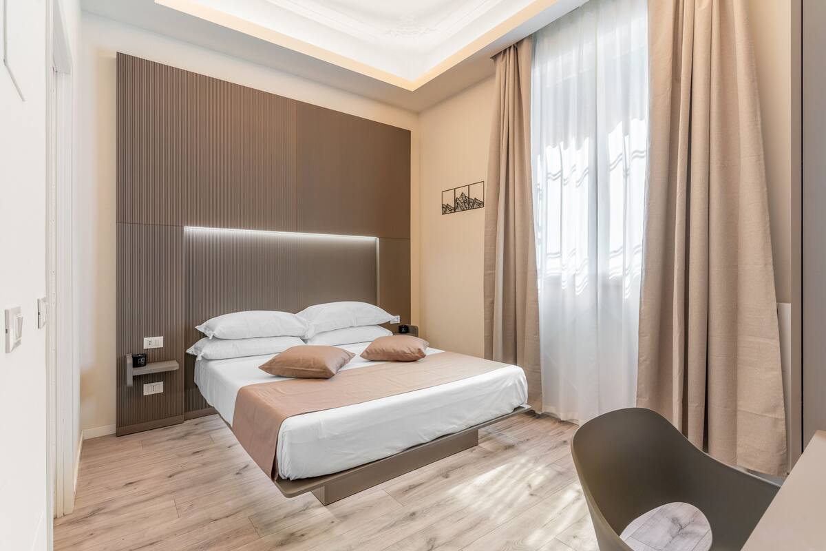 A modern bedroom with a bed, bedside tables, and a chair.