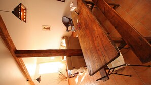 Una habitación con techos altos y vigas de madera a la vista, una mesa grande de madera y una silla.