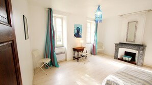 Un dormitorio con cama, chimenea, una mesa y una silla.