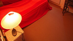 Un dormitorio con dos camas, una ventana, un radiador y un escritorio con lámpara.