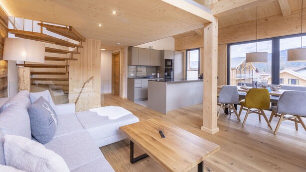 Un interno moderno con soffitto in legno, un divano, un tavolo da pranzo e un angolo cottura.
