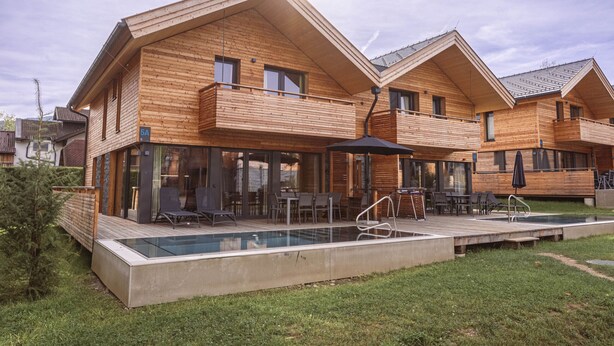 A modern wooden cabin with a glass-enclosed patio and a swimming pool. - Chalet # 5a with sauna & pool (St. Georgen am Kreischberg)