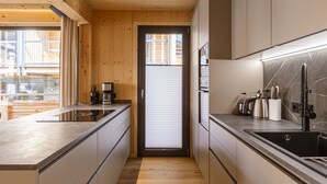A modern kitchen with wooden walls, a central island, and a built-in oven. - Chalet # 5a with sauna & pool (St. Georgen am Kreischberg)