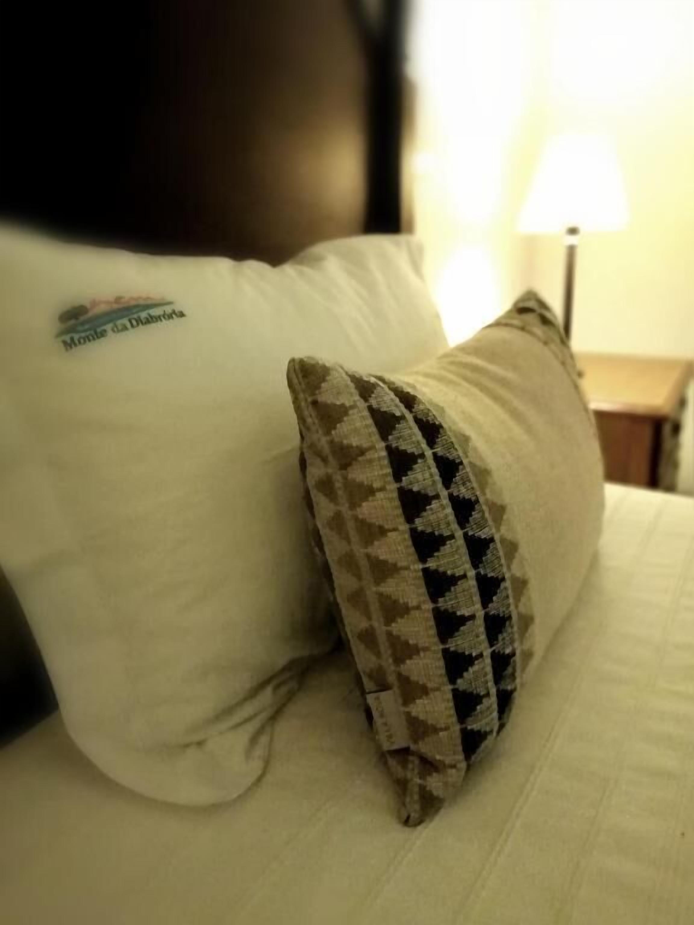 Ein Bett mit einem weißen Kopfkissen und einem gemusterten Kopfkissen.