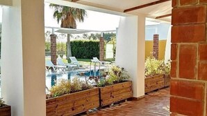 Un espace extérieur abrité comprenant une piscine, des jardinières en bois et un mur en briques.
