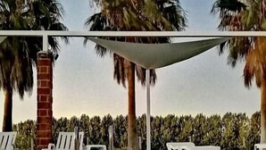 Une piscine aux eaux cristallines, bordée de chaises longues blanches et agrémentée d’un pilier en briques.