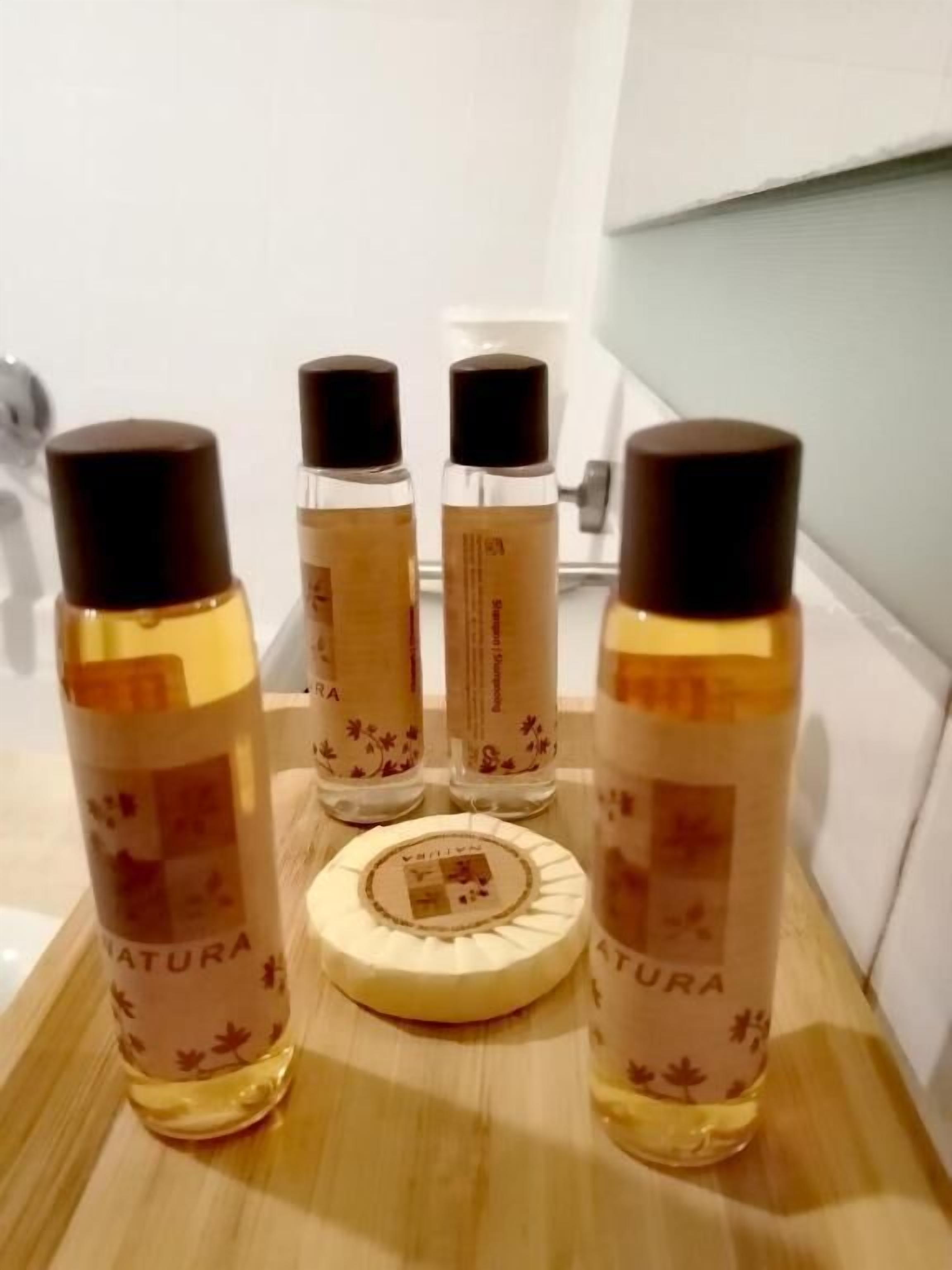 Four bottles of 'Natura' products on a wooden surface.