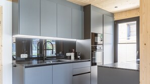 Una cocina moderna con armarios grises, un lavamanos de acero inoxidable y un horno empotrado.