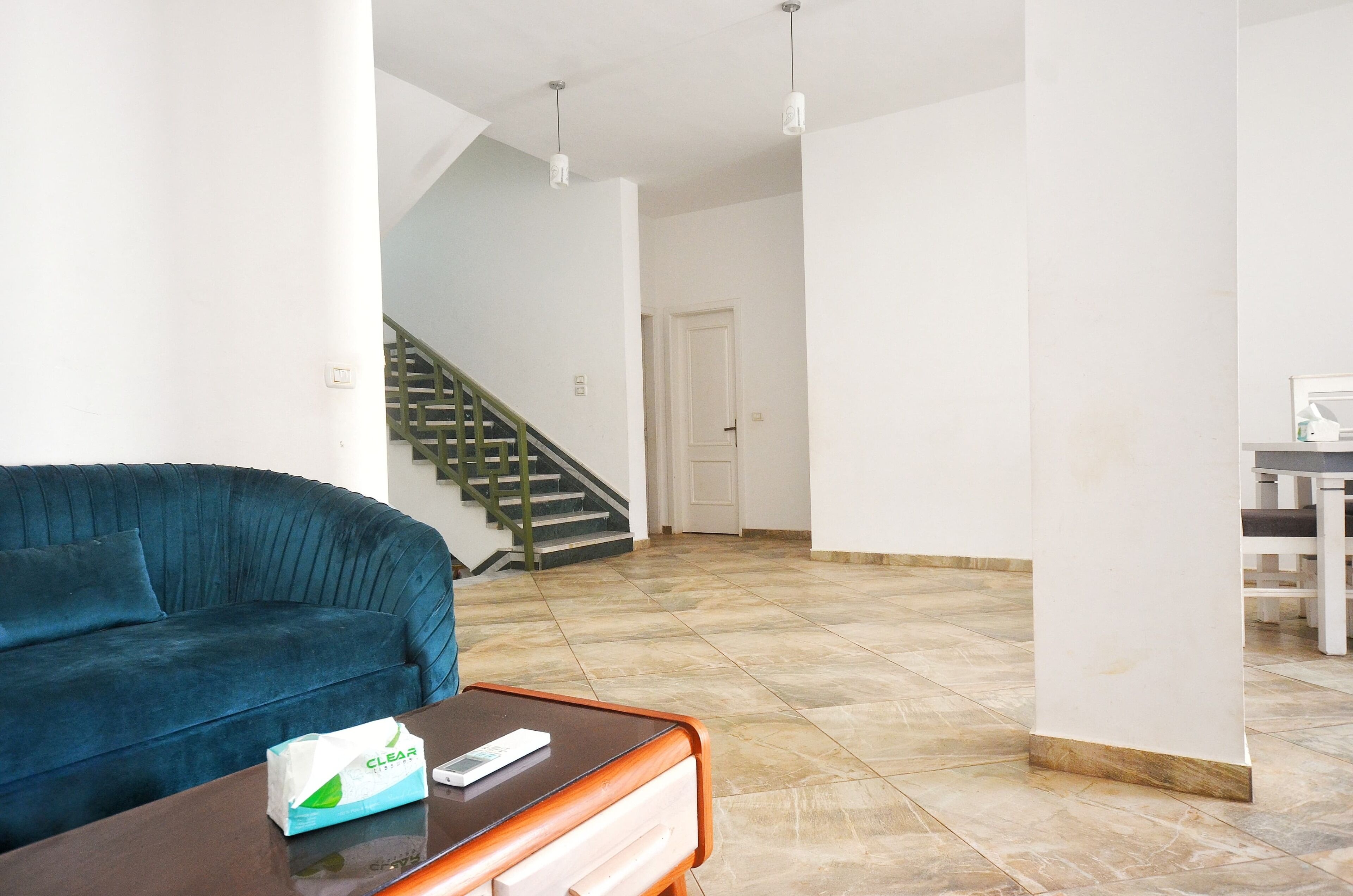 Un vaste espace de vie comprenant un canapé bleu, une table basse en bois et un escalier menant à une autre pièce.
