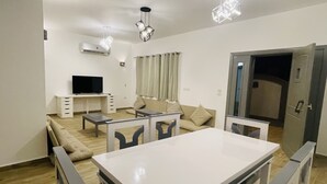A modern living room with a white dining table, sofas, and a TV. - Elite Residence (Dahab)