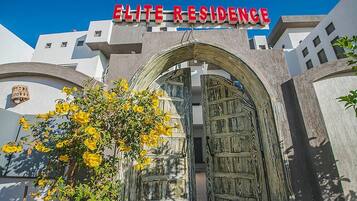 Entrada de un edificio con un letrero que dice "ELITE RESIDENCE" y una puerta de madera grande.